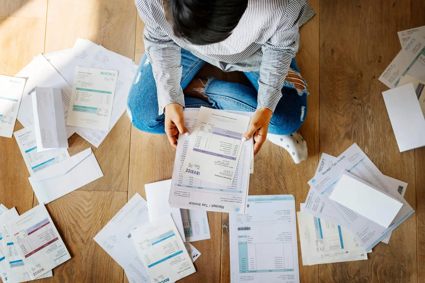 woman seated cross legged on floor surrounded by papers