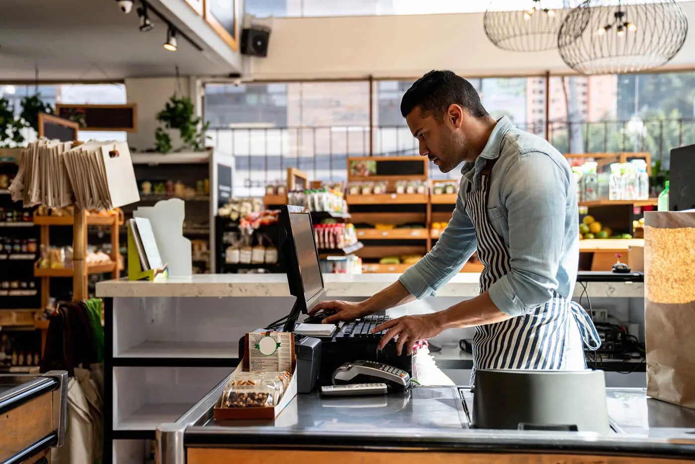 A small business owner looks at his laptop computer while inside his business.