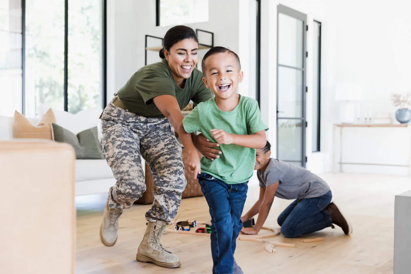 A military mother laughs with her son while playing at home.
