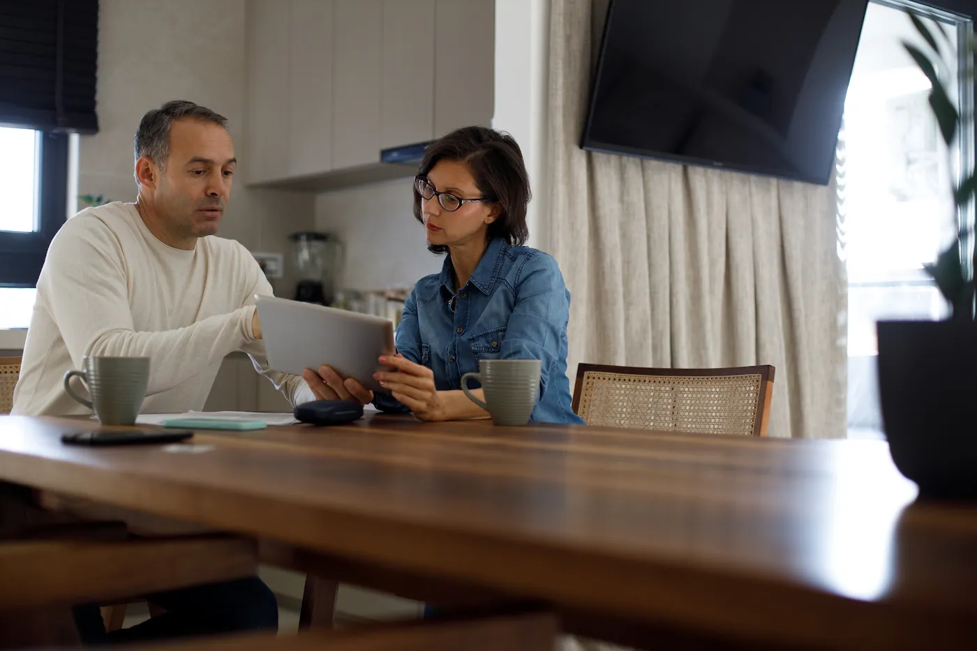 Couple planning finances while sitting at a table looking at a digital tablet.