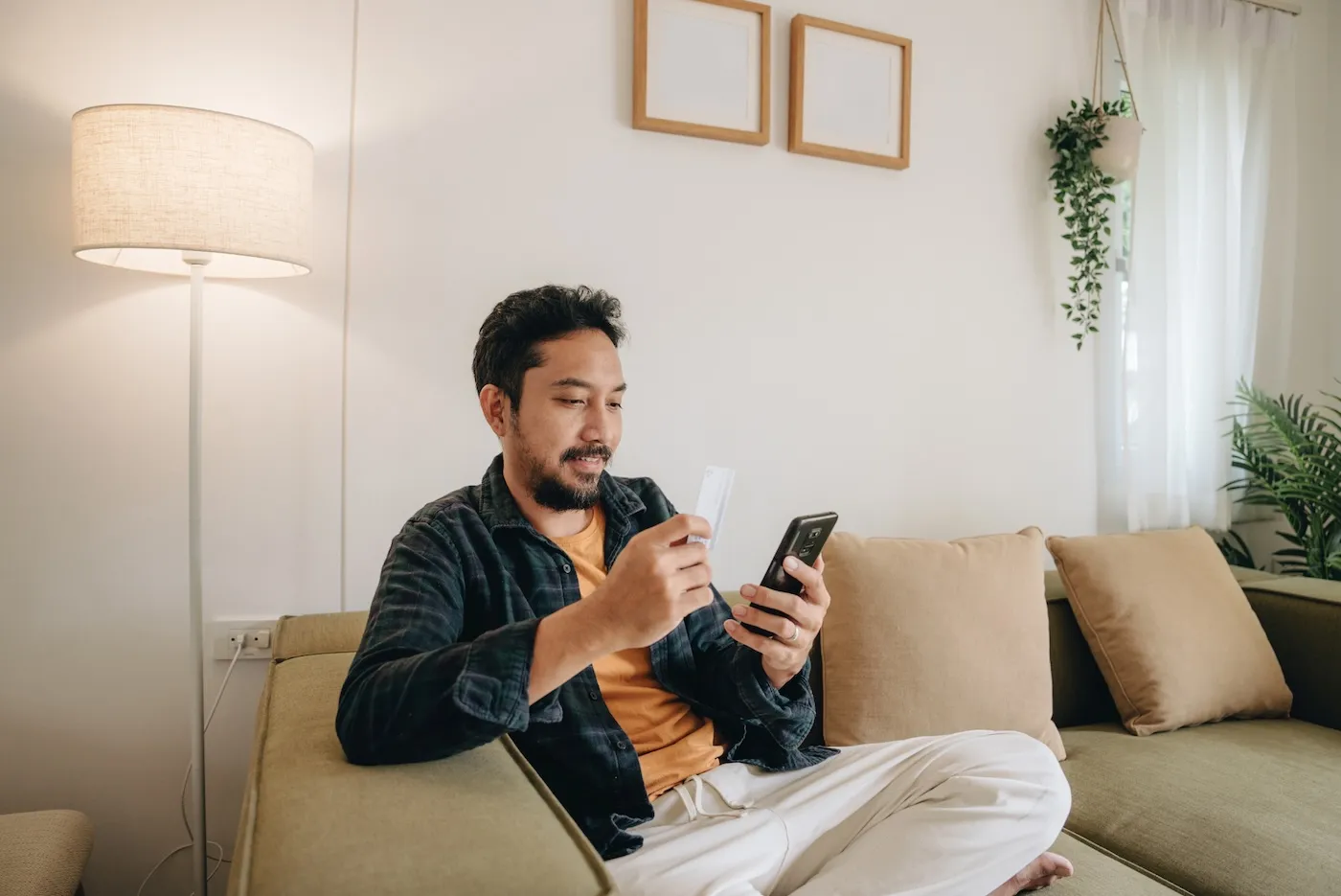 A young man with beard using credit card to make online payment on smartphone.