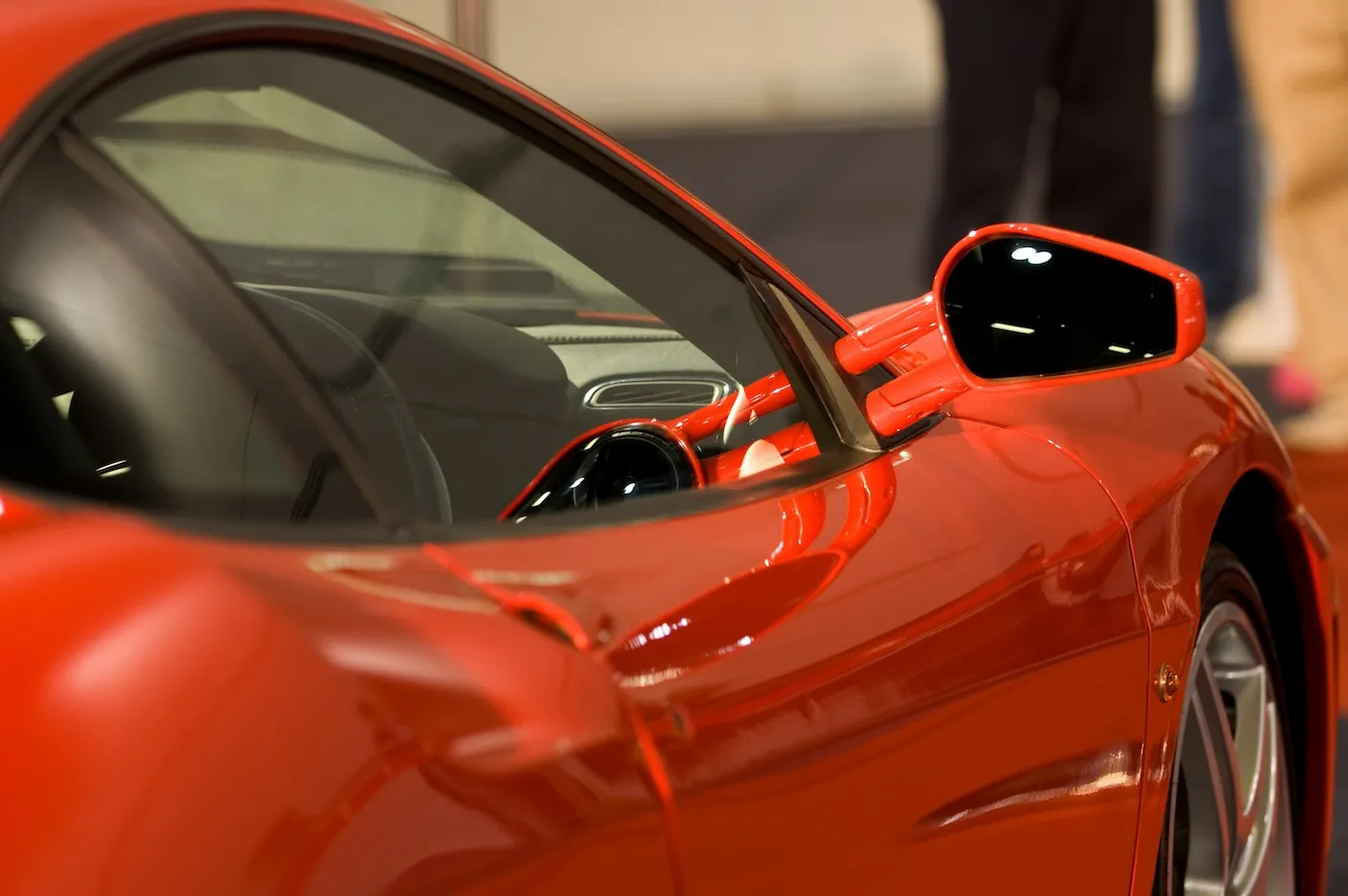 Close shot of right side mirror of exotic shiny red sports car.