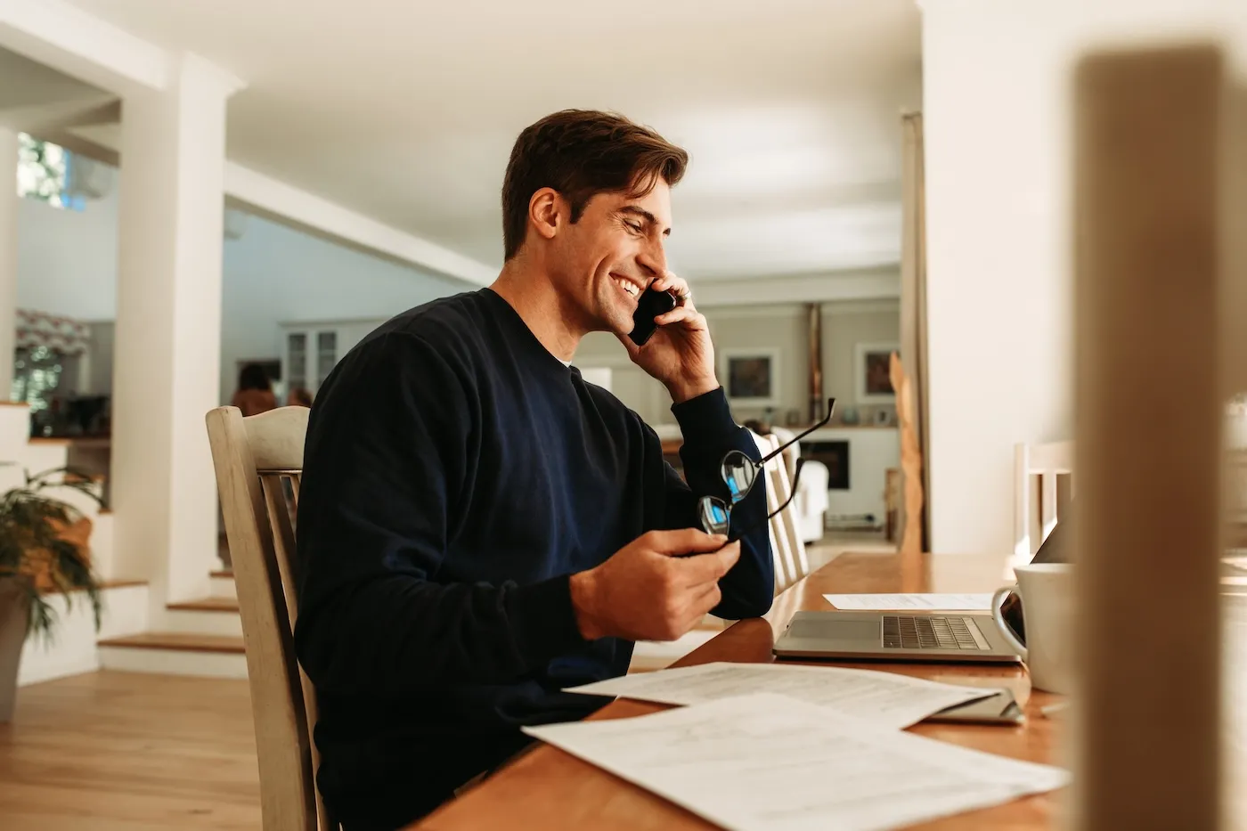 Man working from home with laptop talking on mobile phone. Businessman working from home office.