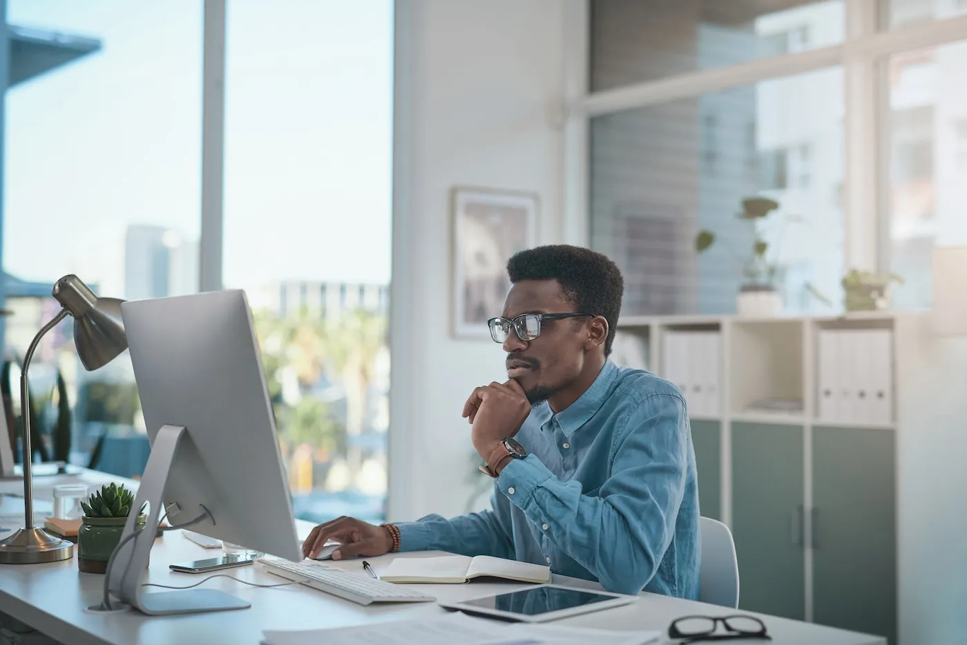 Shot of a young businessman using a computer at his desk in a modern office.