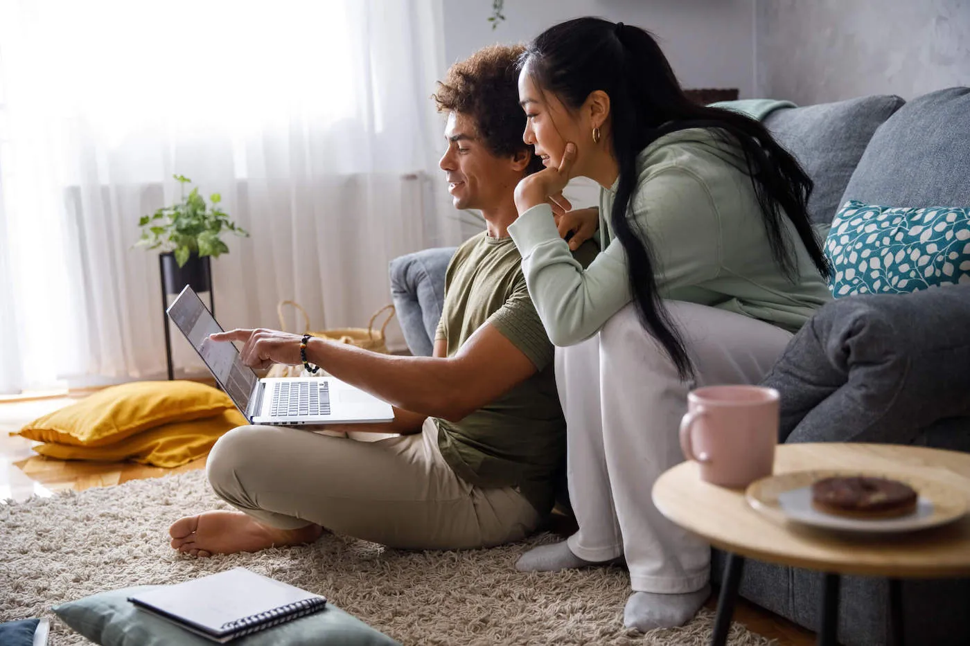 Man and woman looking at laptop while seated in their living room.