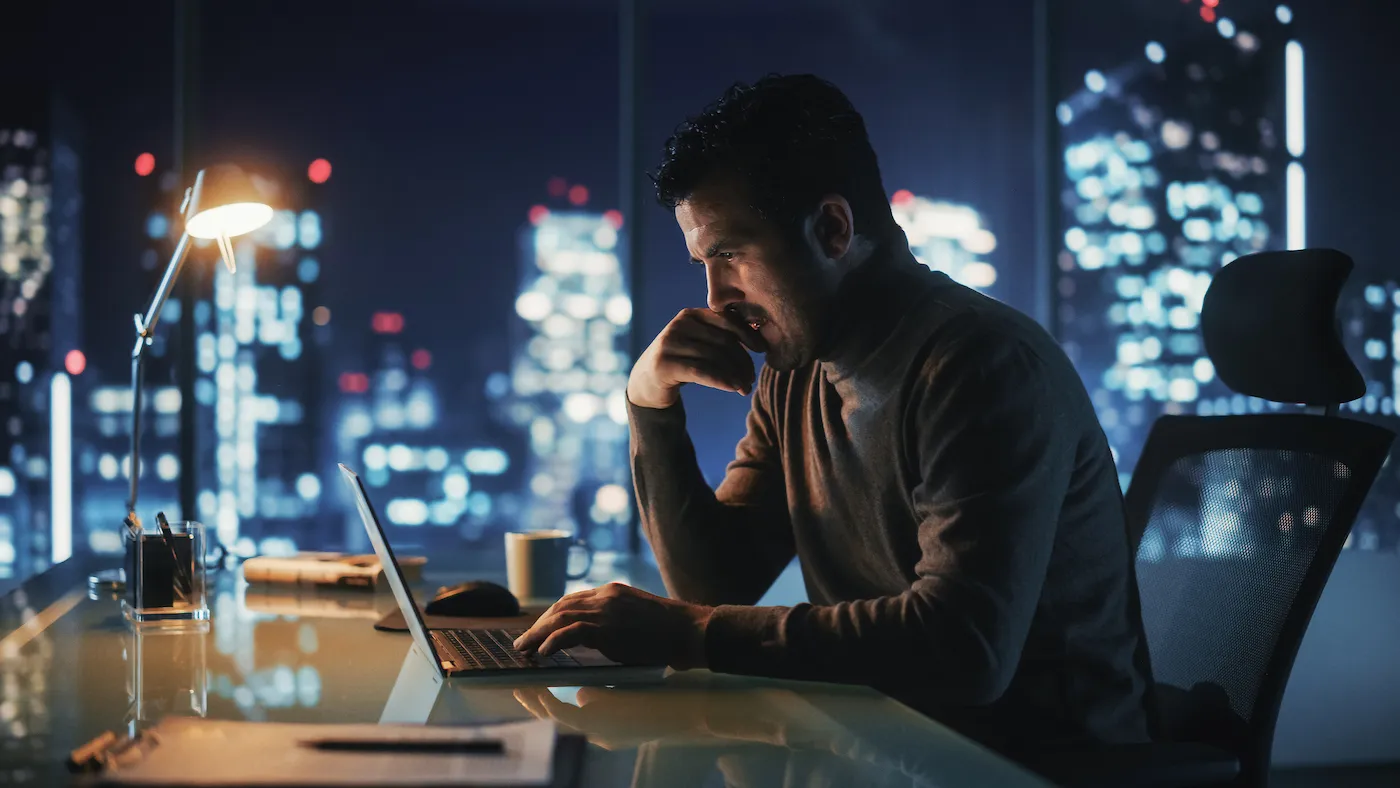 A man who suffered financial losses due to cryptocurrency crashing stares at his laptop, learning how to avoid loss-recovery scams