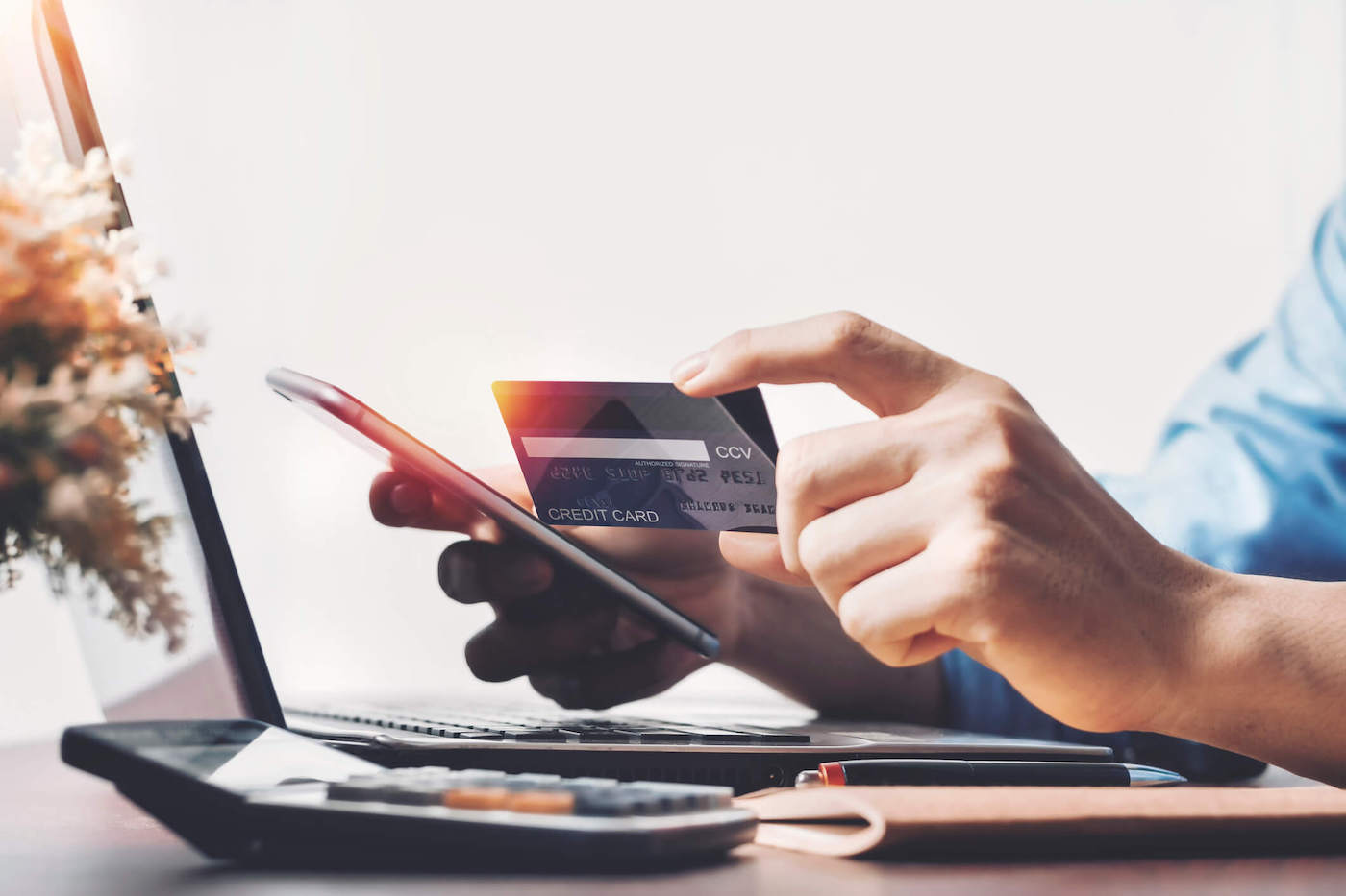 Person holding credit card searching pros and cons of credit cards.