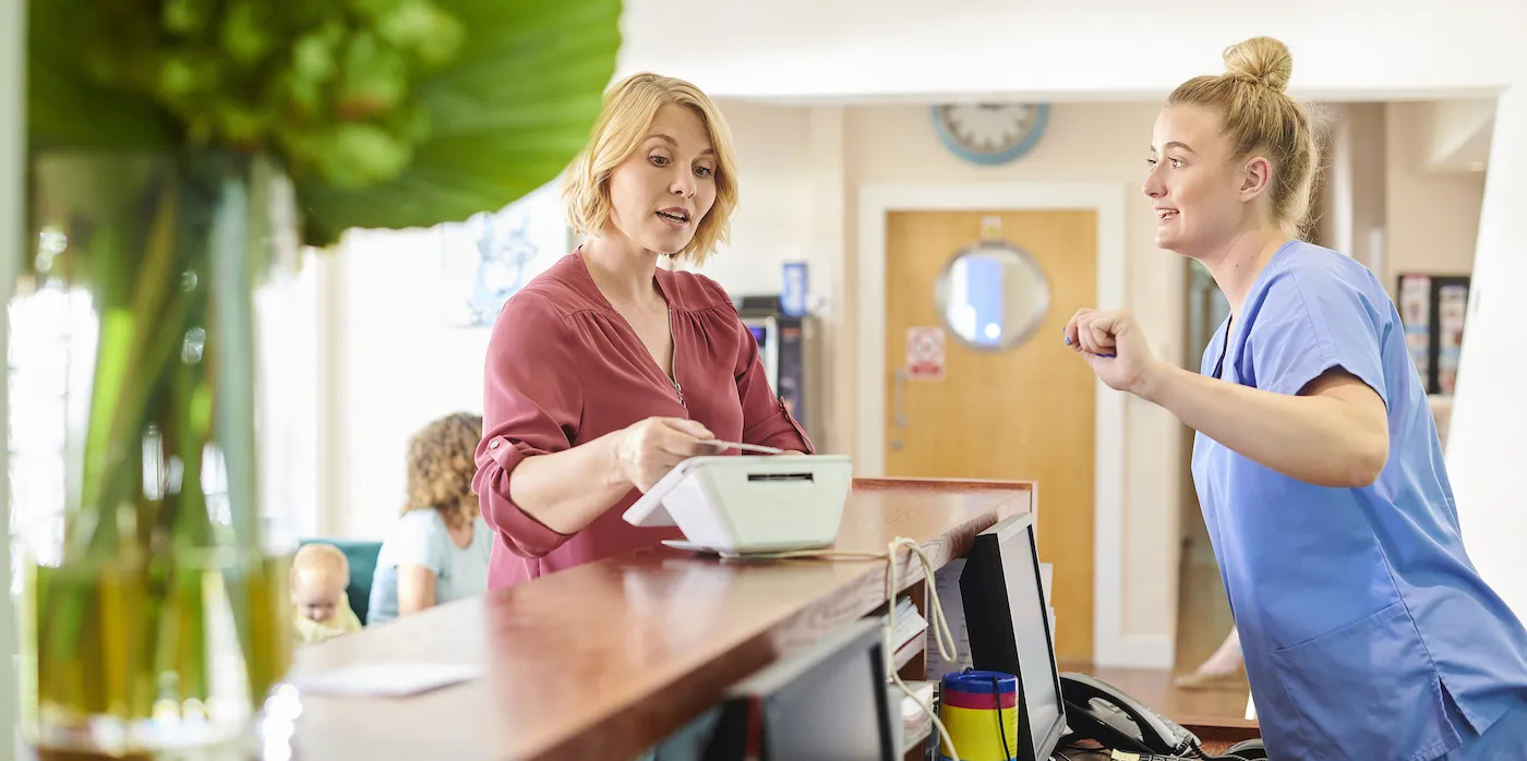 female patient chats to the nurse whilst paying at reception