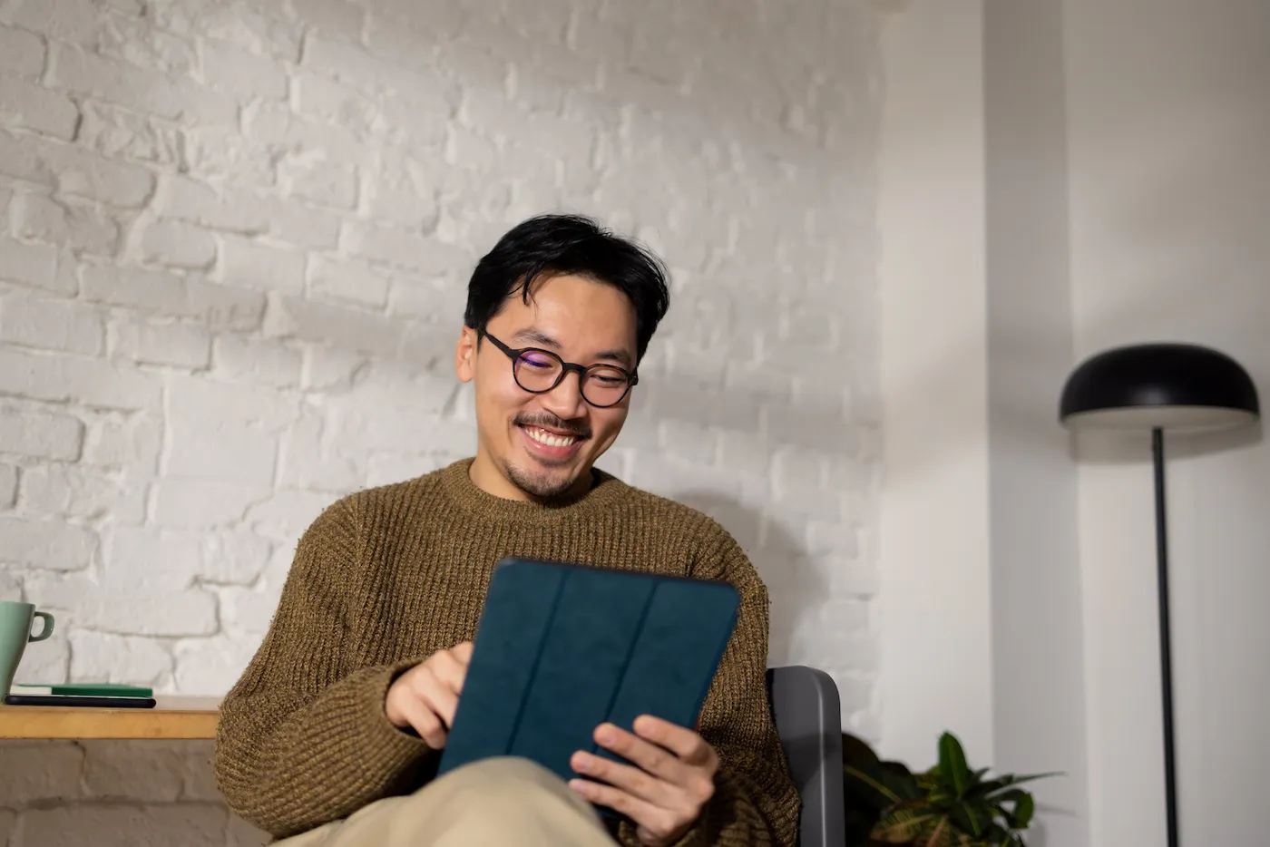 Young man sitting at his home office while looking at CD loan options using tablet