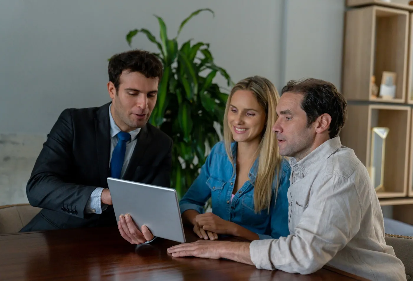 A couple in a meeting with their life insurance agent looking at documents on a tablet.