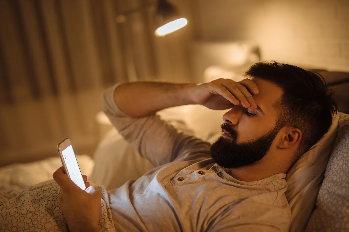 Worried young man reading bad news on smart phone, mortgage lender has failed